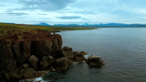 Vista de pájaro de mar tranquilo y acantilados de roca de piedra en la costa de Oregon. Clip. Aérea de la superficie del agua del océano y prados verdes - Foto, Imagen