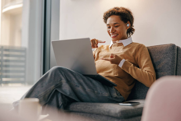 Freelancer feminino positivo tem reunião online enquanto está sentado em coworking acolhedor durante o dia de trabalho - Foto, Imagem