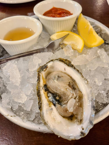 Emelt kilátás egy ínyenc osztriga étel, fűszerekkel és citrusfélékkel a zúzott jégen, bemutatja a luxus tengeri ételek étkezés egy Massachusetts étteremben, 2022 - Fotó, kép