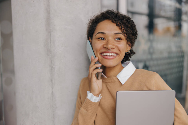Stilvolle Geschäftsfrau telefoniert im modernen Büro mit Laptop  - Foto, Bild