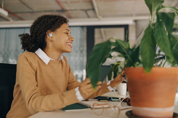 Gerente do sexo feminino sorridente é ouvir música em fones de ouvido durante o tempo de pausa no escritório. Foto de alta qualidade - Foto, Imagem