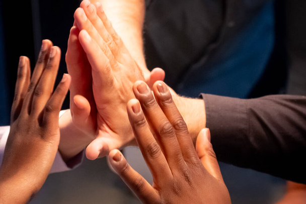 A imagem retrata um grupo de mãos se unindo em um top-cinco, simbolizando o sucesso da equipe, unidade e colaboração. A diversidade dentro da equipe é evidente através da variedade de tons de pele - Foto, Imagem