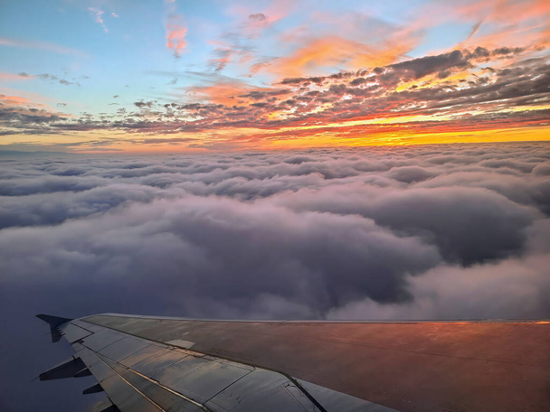 Breathtaking aerial view of vibrant sunset over Bahamas, with airplane wing and sea of clouds - Photo, Image