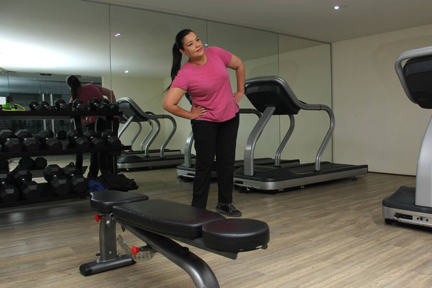 Mujer latina de 40 años se estira para hacer ejercicio en el gimnasio para mejorar su salud y evitar la diabetes y la hipertensión - Foto, imagen