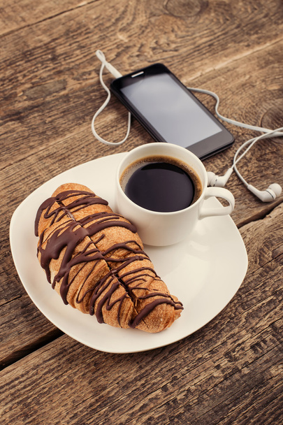 Having coffee and croissants with smartphone and headphones - Foto, Imagem
