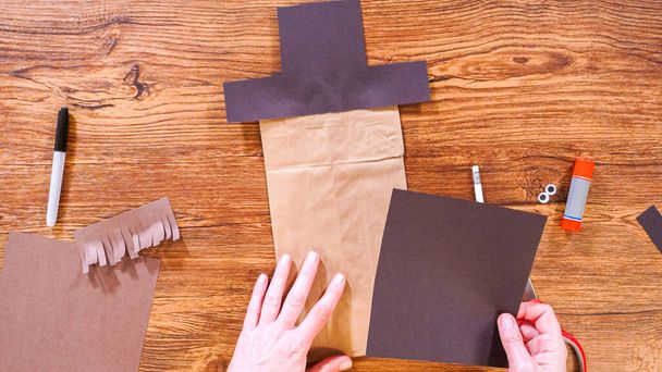 Passo a passo. Deitado. Professor orienta aula on-line através de fazer um fantoche de papel de um saco marrom, usando criativamente uma superfície de madeira como um espaço de trabalho. - Foto, Imagem