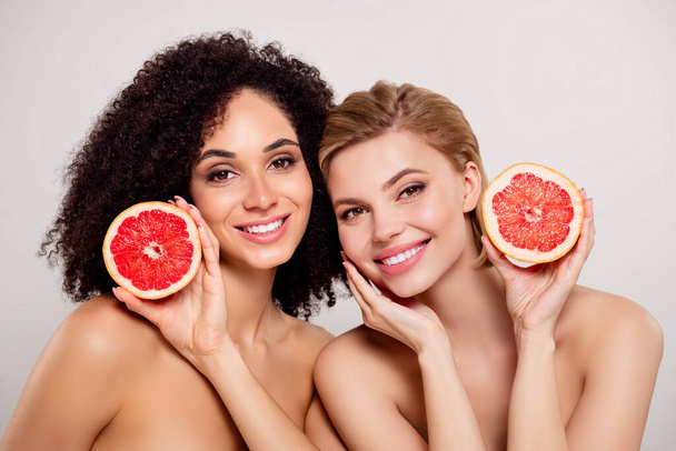 Foto de impresionantes hermosas chicas sonrientes felices sostienen media rebanada de naranja aislada sobre el fondo de color pastel. - Foto, imagen