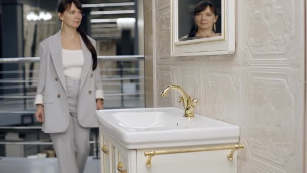 Nainen menossa kylpyhuoneeseen lähellä pesuallas laatta showroom - Materiaali, video