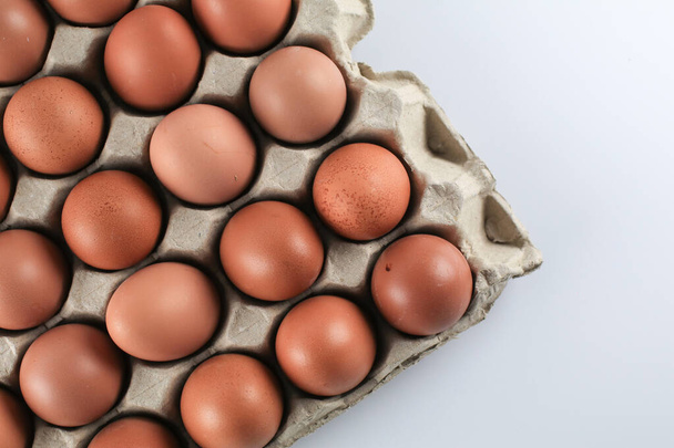 Syrová kuřecí vejce v krabici od vajec na bílém pozadí. Přírodní zdravé potraviny a koncepce ekologického zemědělství. - Fotografie, Obrázek