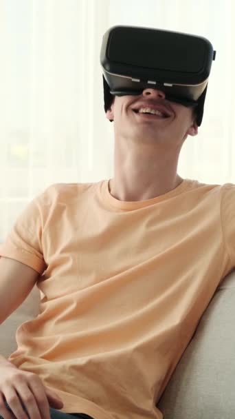 自宅の快適さから新しい次元を探る男。VRヘッドセットを着用し、彼の目に期待感を持つこの若い男は、仮想探査のスリリングな旅に着手します. - 映像、動画