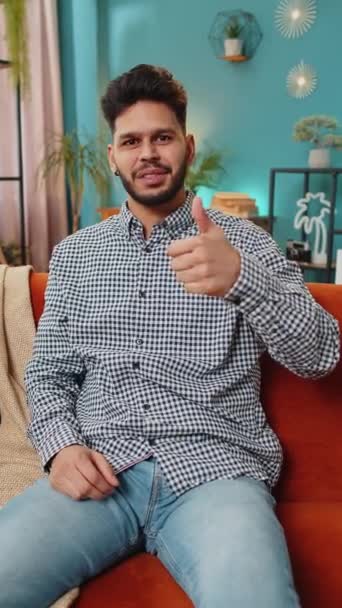 Mint például. Boldog izgatott indiai férfi nézi jóváhagyó kamera mutatja hüvelykujját fel, mint jel pozitív valami jó hír pozitív visszajelzést. Arab fickó ül a kanapén az otthoni nappaliban. Függőleges - Felvétel, videó
