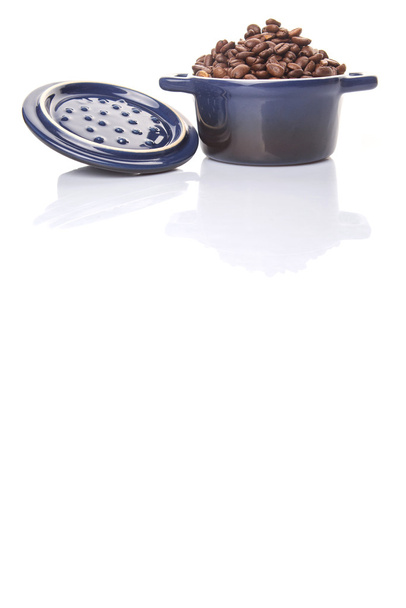 Φρυγμένους κόκκους καφέ σε ένα μπλε κεραμικό δοχείο πάνω από το λευκό φόντο - Φωτογραφία, εικόνα