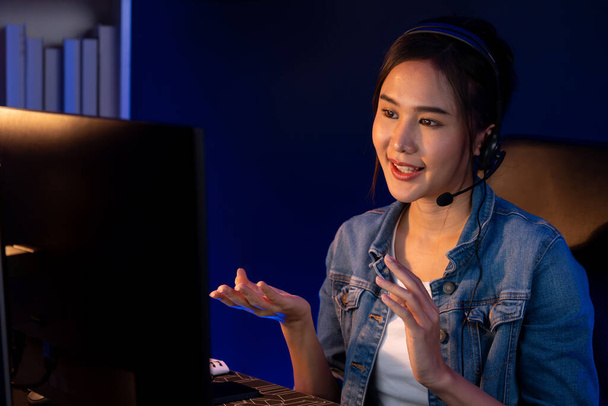Host channel Asian influencer talking in broadcast streaming online wearing headsets on social media with pc recording, greeting listeners and coaching market online at neon modern studio. Stratagem. - Photo, Image