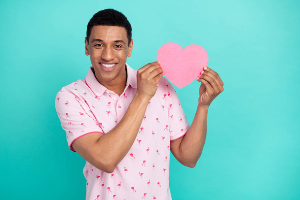 Photo of satisfied handsome guy dressed casual polo holding paper heart postcard on valentine day isolated on teal color background. - Φωτογραφία, εικόνα