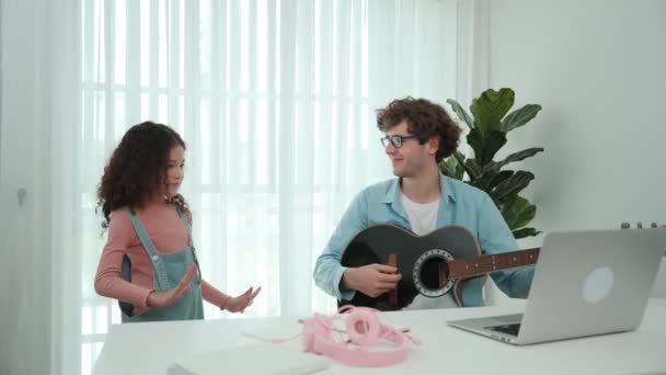 Attractive caucasian dad playing guitar while cute daughter dancing to music. Happy father and american girl spend time together while smart child move to music. Family recreation concept. Pedagogy. - Footage, Video