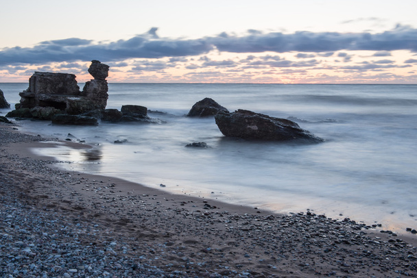 κύματα σύνθλιψη πέρα από τους βράχους στο ηλιοβασίλεμα - Φωτογραφία, εικόνα