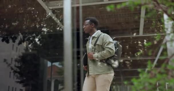 Black man, building and walk with backpacker to work in confidence, formal and tablet in New York. Male person, entrepreneur and office to business meeting for startup company opportunity and funding. - Footage, Video
