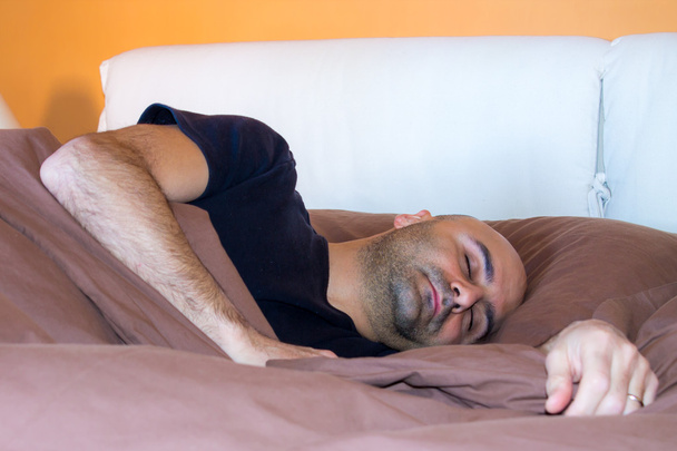 Ο άντρας κοιμάται στο κρεβάτι - Φωτογραφία, εικόνα