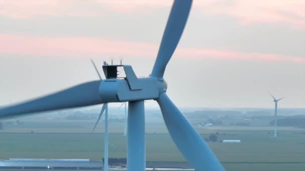 Aerial Arc Shot captura la majestuosidad de las imponentes turbinas eólicas en medio de las serenas tierras de cultivo de Ohios en el crepúsculo, transmitiendo una armoniosa mezcla de energía sostenible y naturaleza. - Imágenes, Vídeo