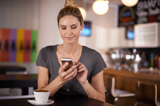 Onnellinen nainen, kirjoittamalla ja puhelimitse kahvia viestintään, sosiaalisen median tai verkostoitumisen kahvilassa. Naishenkilö hymy mobiili älypuhelin online chattailuun, kutoma tai app sisätiloissa ravintola. - Valokuva, kuva