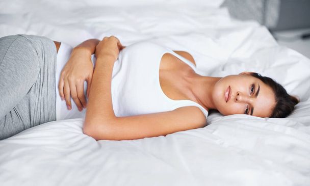 Woman, stomach ache and pain in bed with virus, menstruation cramps or endometriosis. Gut health crisis, colon blockage or constipation with bloating from stress, PMS or IBS with appendicitis at home. - Photo, Image