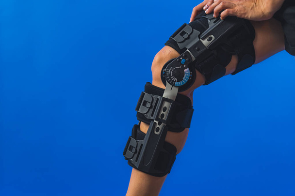 paciente mulher com bandagem moderna compressão joelho cinta que tem um botão de controle de movimento de ângulo. Foto de alta qualidade - Foto, Imagem