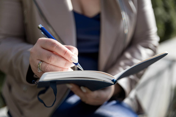 A mulher segura um bloco de notas e uma caneta. Ela está fazendo anotações em seu livro semanal. Espaço de cópia - Foto, Imagem