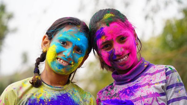fiatal aranyos vidám kislány gyerek alkalmazott holi színek por mutatja színes kéz a kamera alatt holi fesztivál ünnepe - Fotó, kép