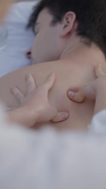 Sahildeki genç çocuğa masaj yapan masözün omuzlarının üstünden FullHD dikey video. - Video, Çekim