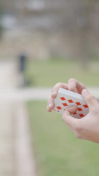 Zblízka boční záběr muže kouzelníka šourání s kartami, než dělá triky ve dne s výhledem na kamenné stěny v pozadí. - FullHD Vertikální video - Záběry, video
