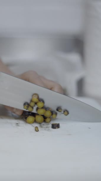 Close side view of chef-kok snijgroenten op aanrecht, geen gezicht - FullHD Verticale video - Video