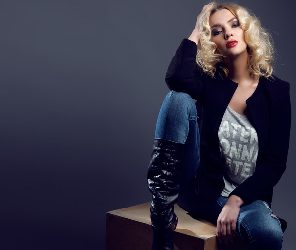 Mode portret van blonde vrouw in jeans en trendy zwarte jas. - Foto, afbeelding