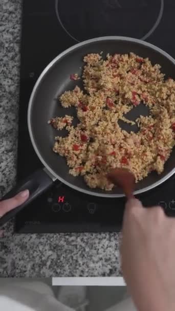 Person, die eine gesunde Mahlzeit mit braunem Reis auf einem Elektroherd zubereitet. Overhead Shot - Vertikal - Filmmaterial, Video