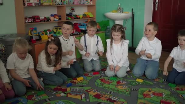 Děti v bílém oblečení jsou zaměřeny na hru s gesty, obklopené hračkami a světlým interiérem. - Záběry, video