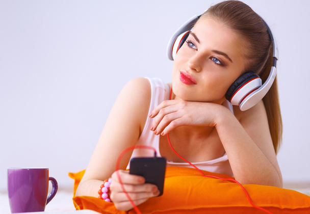 Young woman lying on floor and listen to music - Photo, Image