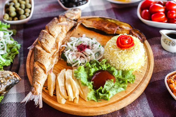 Een houten bord tot aan de rand gevuld met een assortiment van heerlijke en smakelijke gerechten, waaronder vlees, groenten en desserts. - Foto, afbeelding