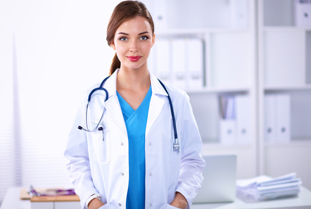 Portrait of young woman doctor with white coat standing in hospital - Foto, immagini