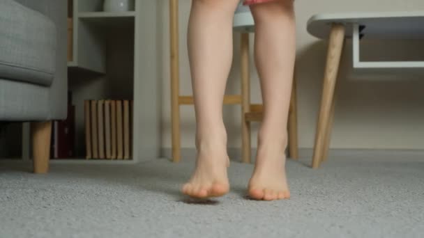 Gelukkig kind springen op blote voeten op tapijt, benen close-up, slow motion - Video