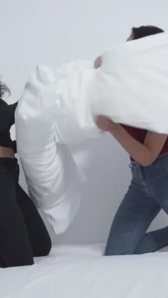 Dwie kobiety śmiejące się podczas walki na poduszce na łóżku. średni strzał - pionowy 1080 - Materiał filmowy, wideo