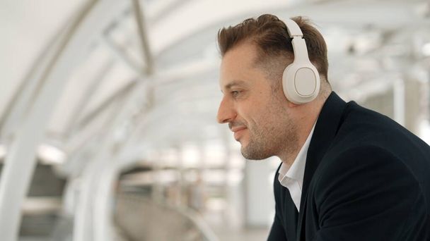 Közeli kép üzletember mozog a fejét a zene, miközben pihentető zenét hallgat a fejhallgató. Kaukázusi menedzser visel headset, miközben élvezze hallgatni és mozgatni gesztus és mozgás városi Urbane. - Fotó, kép