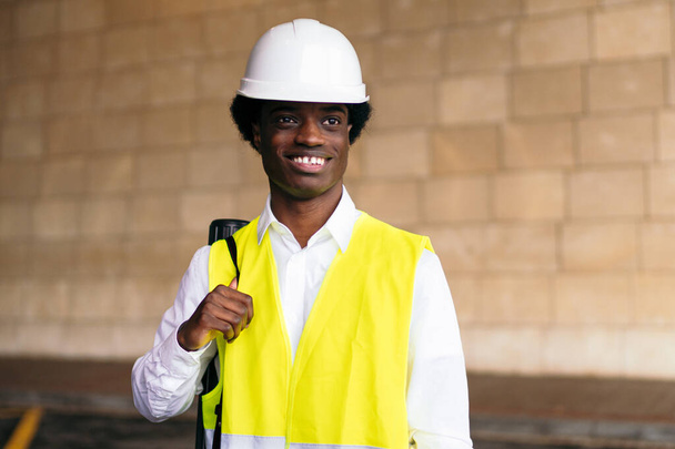 African architect entrepreneur in safety vest and helmet, smiling broadly. - Photo, Image
