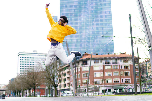 Ζωντανός Αφρικανός νεαρός πηδάει ψηλά με ευτυχία στην πόλη.. - Φωτογραφία, εικόνα