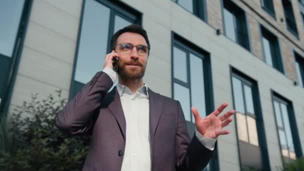 Lachend lachen Kaukasische man blij vrolijk volwassen professionele ondernemer mannelijke succesvolle zakenman praten smartphone in de stad antwoord zakelijk gesprek in de buurt van kantoor buiten praten mobiele telefoon glimlach - Video