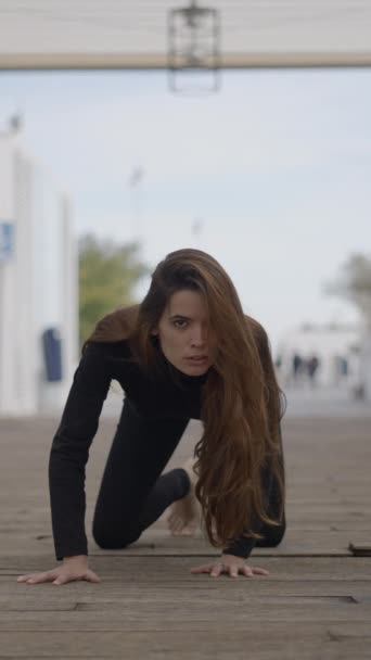 Mujer joven al aire libre se mueve a cuatro patas como un gato, vista estática al suelo - 1080 vídeo vertical - Metraje, vídeo