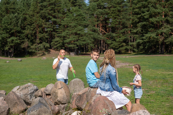 Uma família desfruta de uma aventura ao ar livre em uma clareira pinhal, Esta imagem encapsula o espírito de brincadeira de infância e escapadas familiares na natureza. Foto de alta qualidade - Foto, Imagem