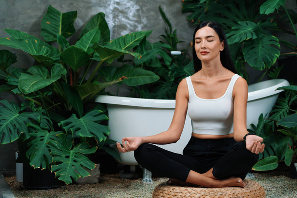 Mujer joven haciendo yoga matutino y meditación en jardín natural con hoja de planta, disfrutando de la soledad y practicando poses meditativas. Actividad de atención plena y estilo de vida mental saludable. Blithe. - Foto, Imagen