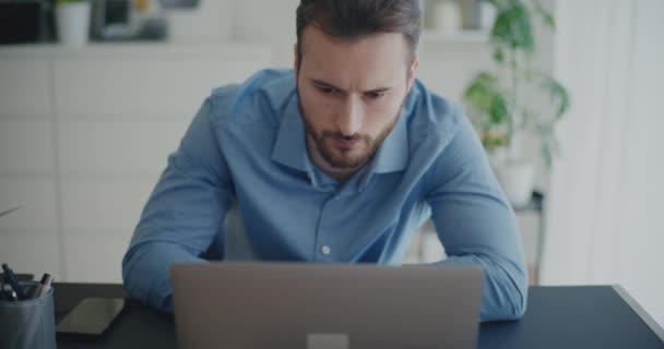 Κλείδωμα στιγμιότυπου αφοσιωμένου νεαρού άνδρα επιχειρηματία που χρησιμοποιεί φορητό υπολογιστή στο γραφείο του σε εταιρικό χώρο εργασίας - Πλάνα, βίντεο