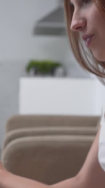 Mädchen mit Tablet sucht, während sie in einem Sofa sitzt Tilt-up - Vertikal - Filmmaterial, Video