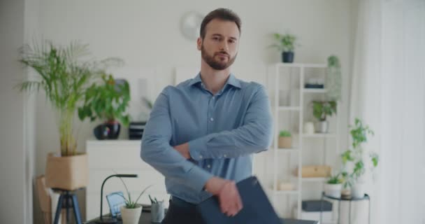 Lezárt portré fiatal jóképű üzletemberről, aki digitális táblagépet tart, miközben keresztbe tett kézzel áll a vállalati munkaterületen - Felvétel, videó