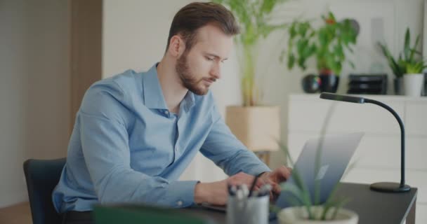 Dedicado joven tipeo profesional masculino mientras se utiliza el ordenador portátil en el escritorio en el espacio de trabajo corporativo - Imágenes, Vídeo